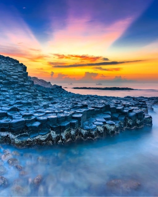 The Giant's Causeway basalt columns in County Antrim, Northern Ireland, lit by an orange and purple sunset