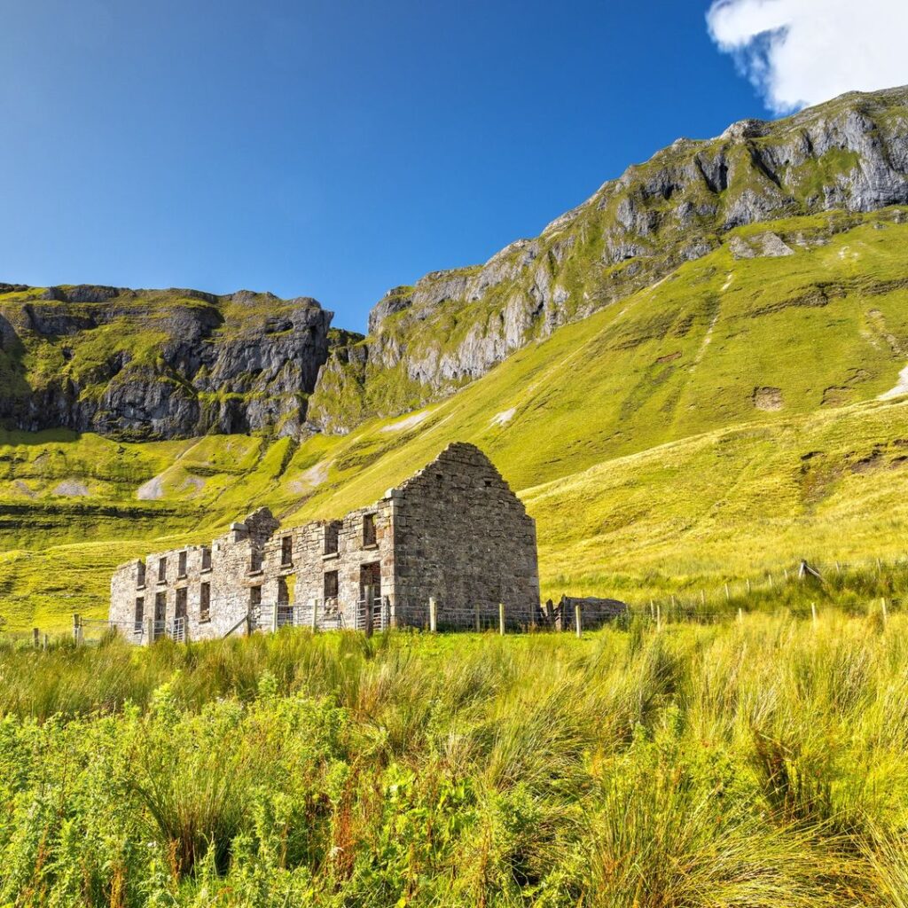 Ruined stone farmhouse in the Gleniff Horseshoe valley, County Sligo, with the limestone cliffs of the Dartry Mountains rising behind it