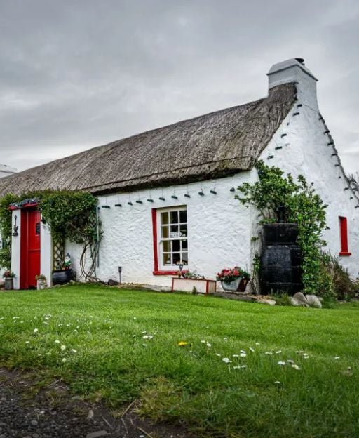 Whitewashed thatched cottage in the Irish countryside with red door