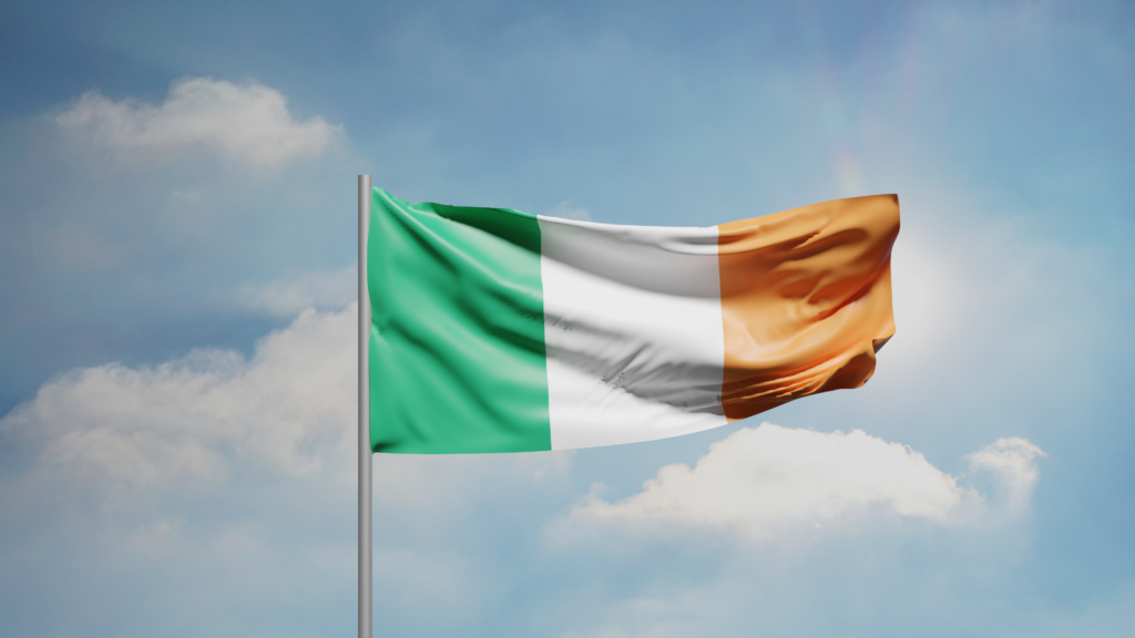 The Irish tricolour flag (green, white and orange) flying against a blue sky