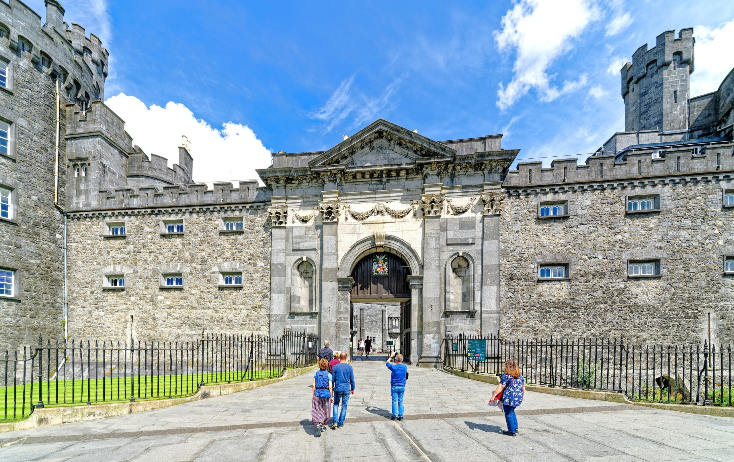 Visitors walking through the ornate entrance archway of Kilkenny Castle, County Kilkenny, Ireland