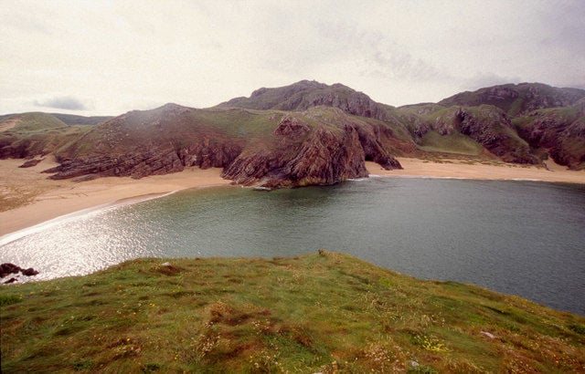 View of Boyeeghter Bay (Murder Hole Beach) from the headland on the Rosguill Peninsula, County Donegal, showing golden sand framed by dark cliffs and the Atlantic