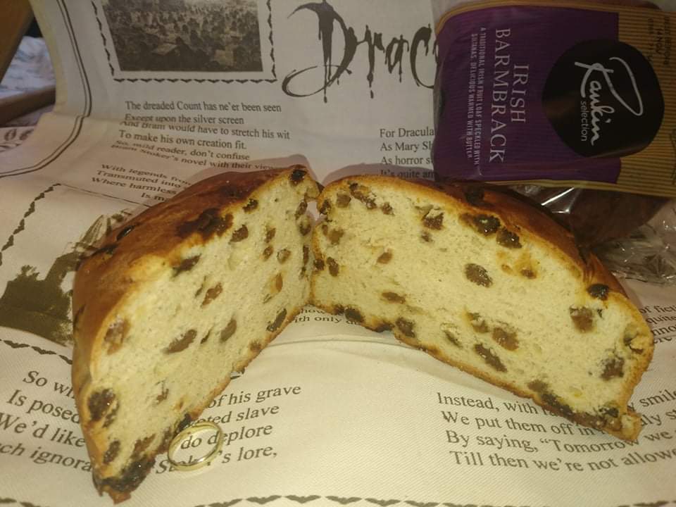 Sliced Irish barmbrack fruit loaf with visible raisins and a gold ring charm, a traditional Halloween treat