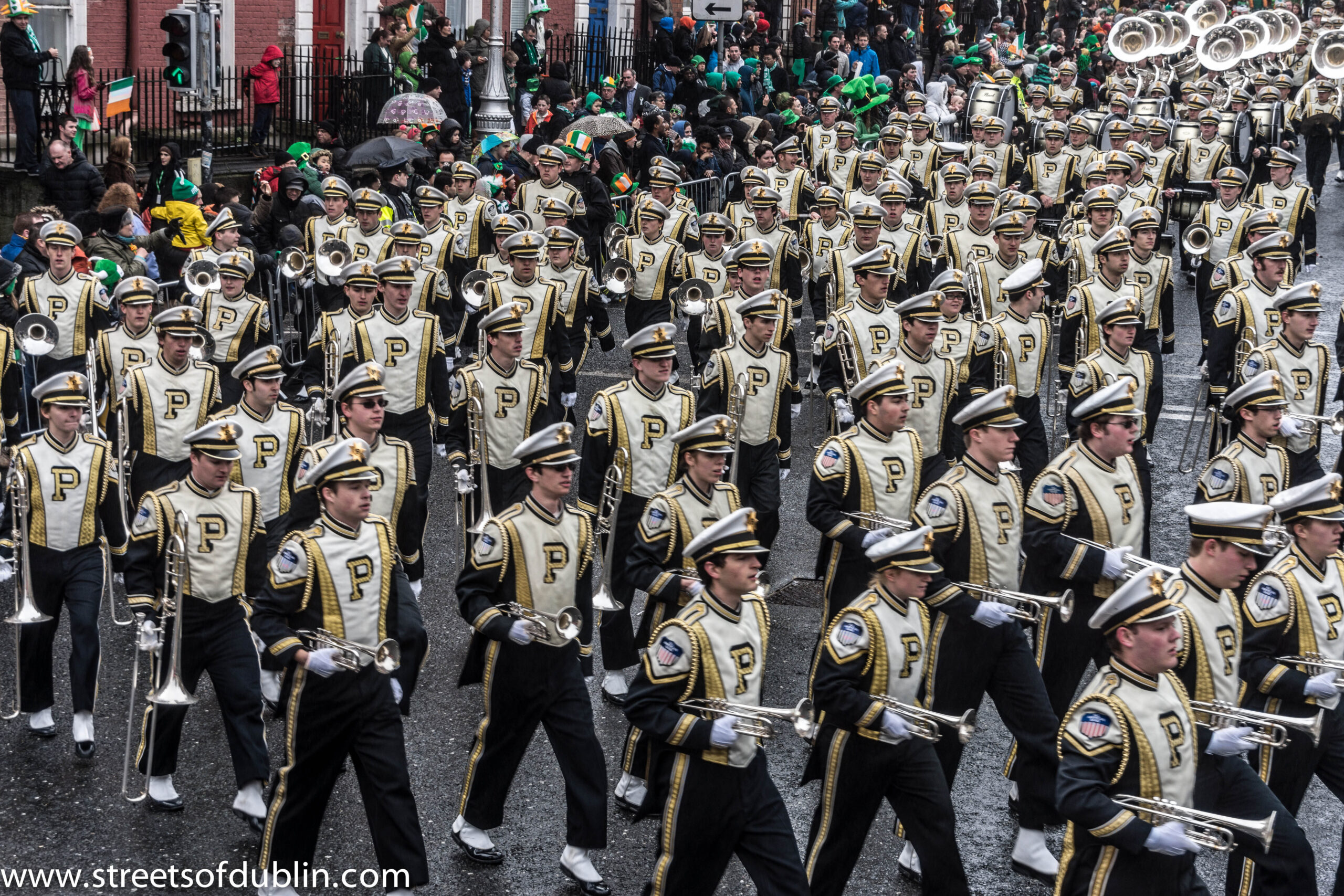 Crowds in green and Irish tricolour flags watch a marching band parade down a Dublin street during the St Patrick's Festival