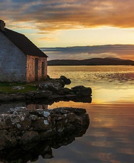 Connemara lake with a stone cottage at sunset, County Galway, Ireland