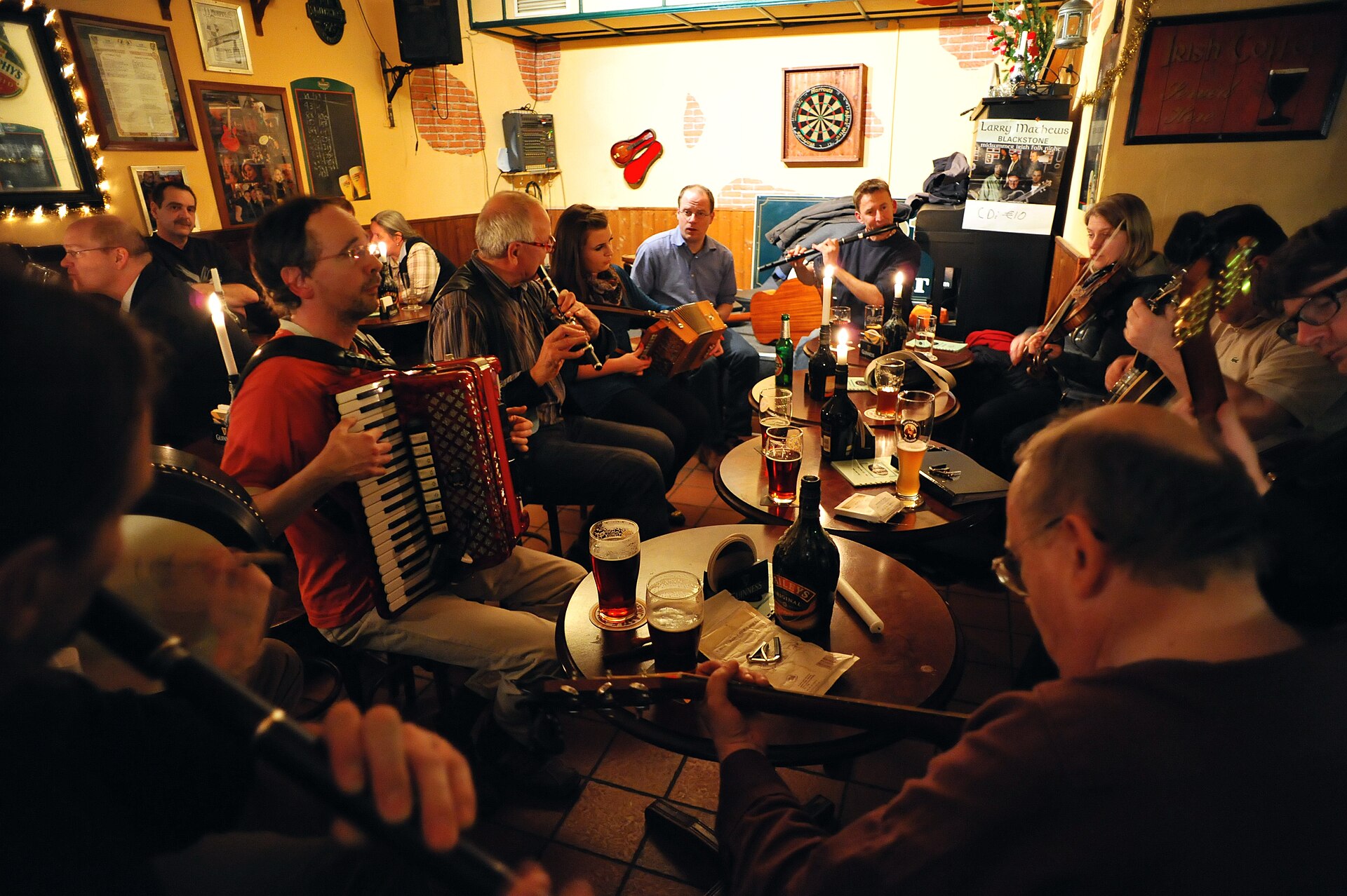 Musicians playing accordion, tin whistle, fiddle and banjo during a traditional Irish folk music session in a pub