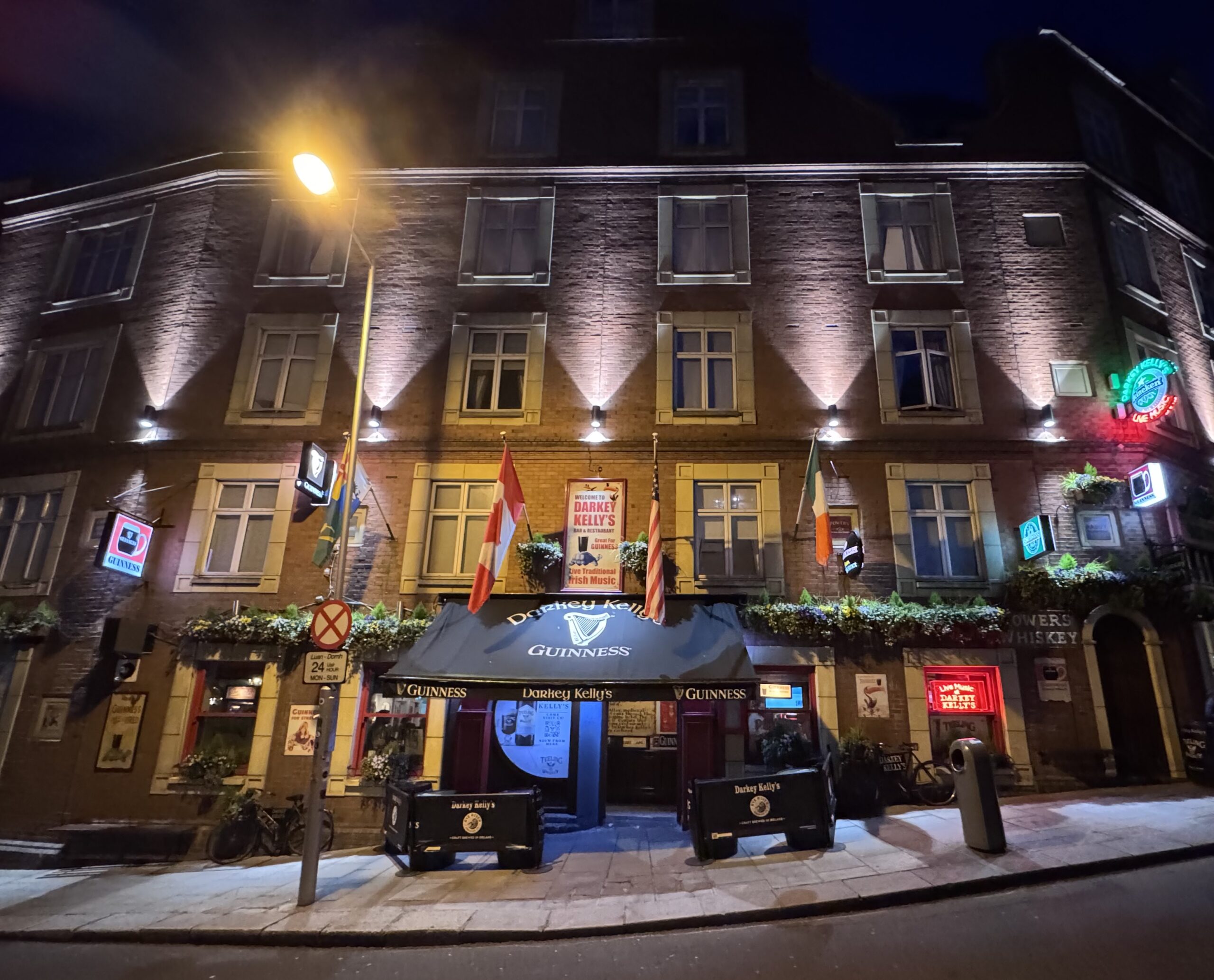 Traditional Irish pub exterior lit up at night in Dublin, with Guinness signage and the Irish tricolour