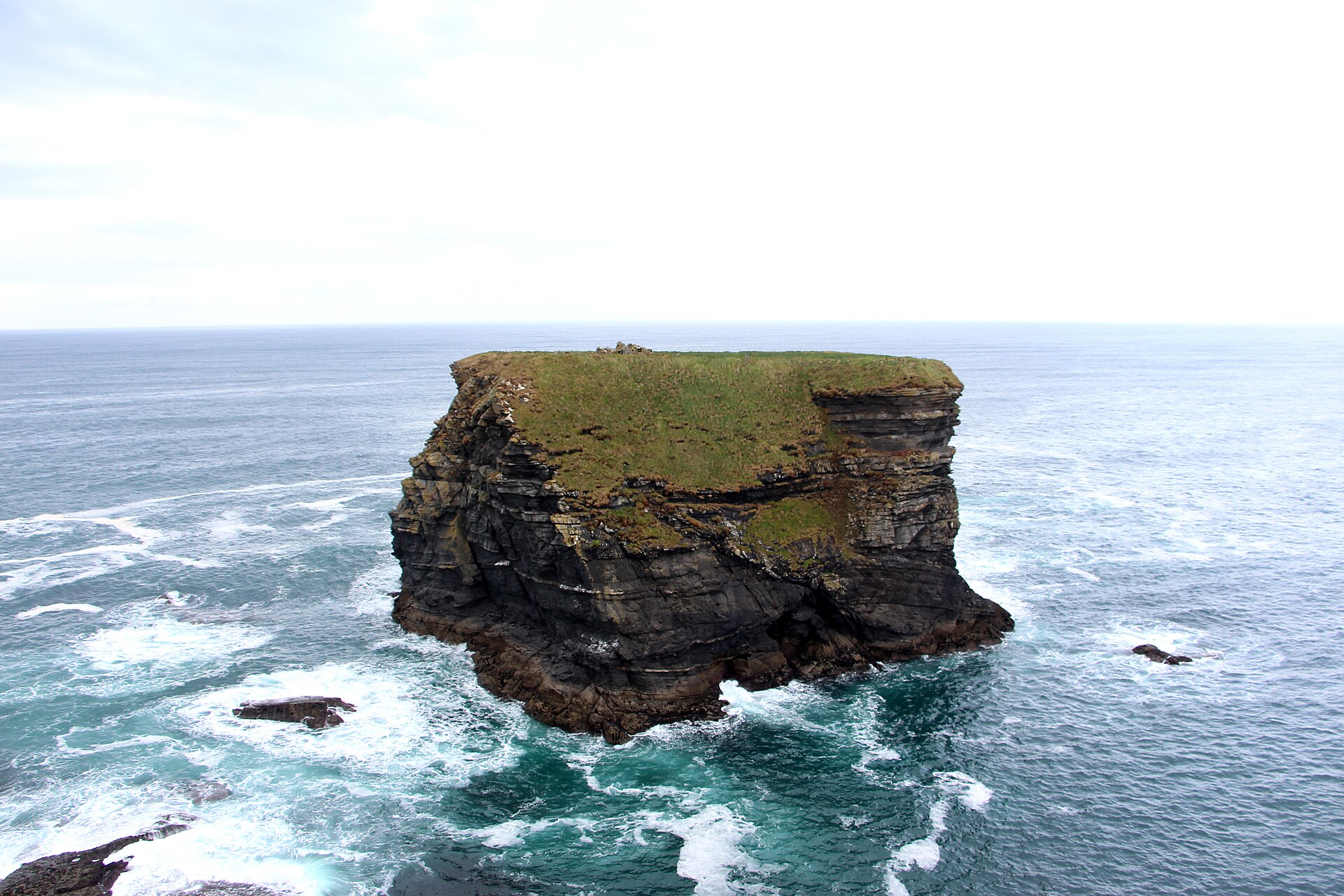 Bishop's Island, a flat-topped sea stack near Kilkee, County Clare, with the ruins of an early Christian monastic settlement visible on its grassy summit