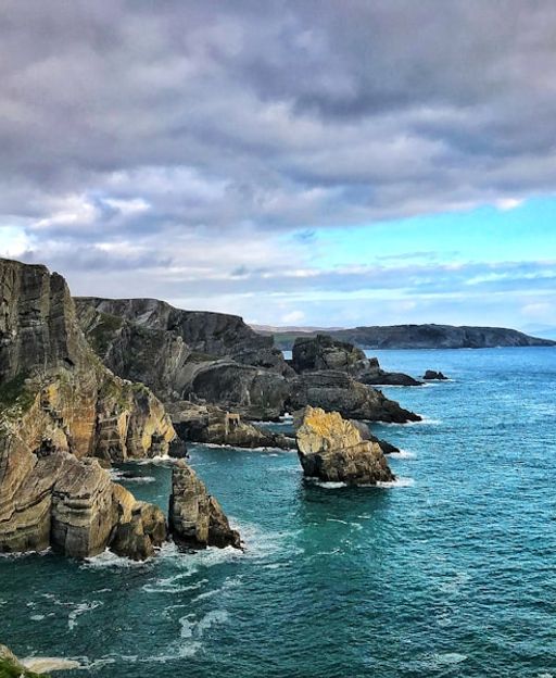 Dramatic cliffs of the Irish west coast with Atlantic Ocean and distant island visible on the horizon