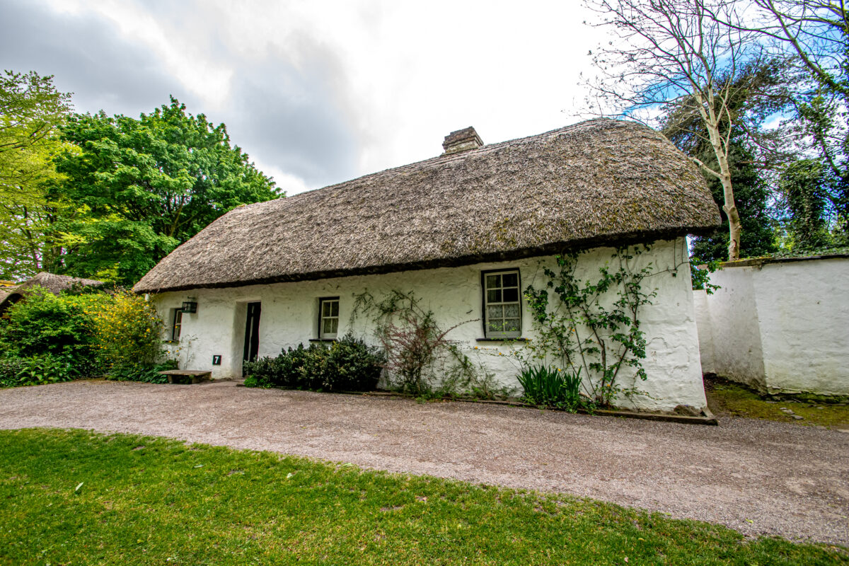 A traditional whitewashed thatched cottage at Bunratty Folk Park, County Clare, Ireland, representing the home left behind by millions of emigrants