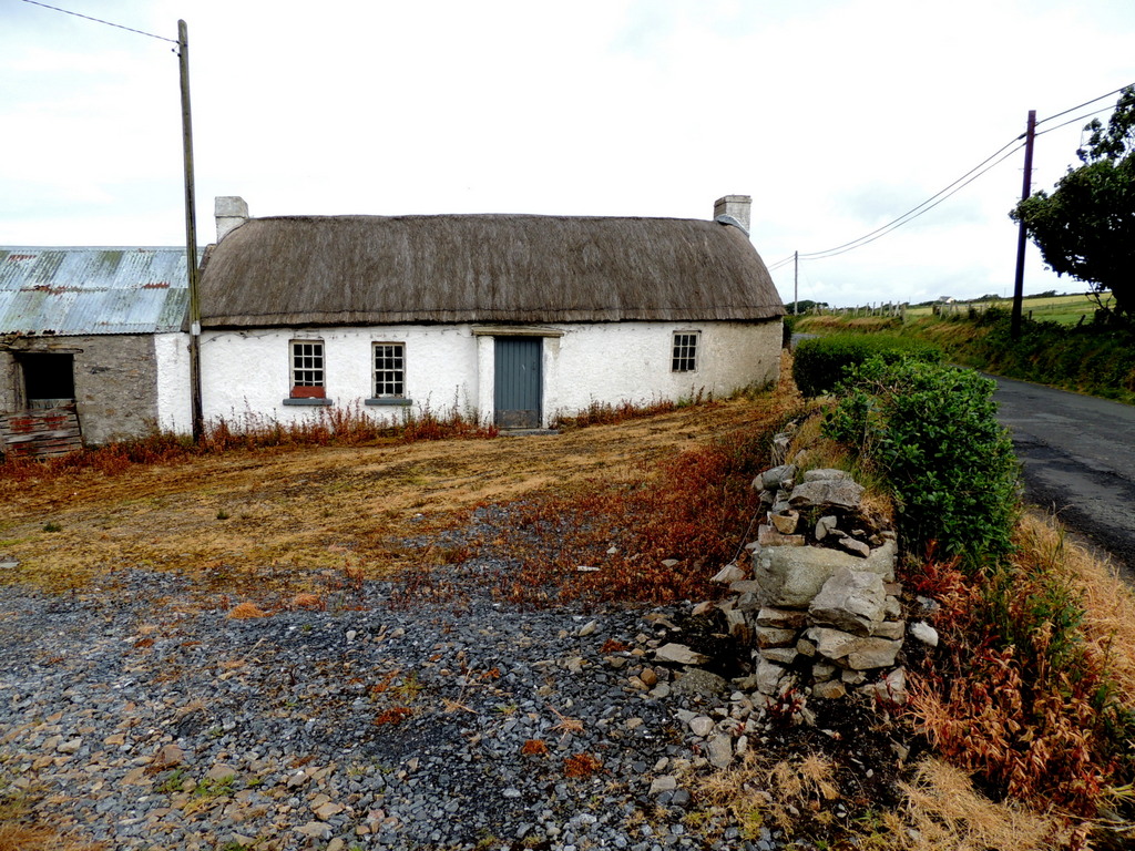 Whitewashed thatched-roof Irish cottage in the countryside, the kind of remote rural home that once hid an unlicensed sheebeen