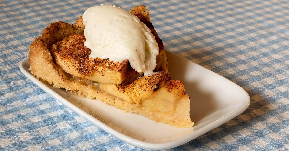 A slice of Kerry apple cake with a scoop of vanilla ice cream, showing its golden sugared crust and soft apple-studded sponge