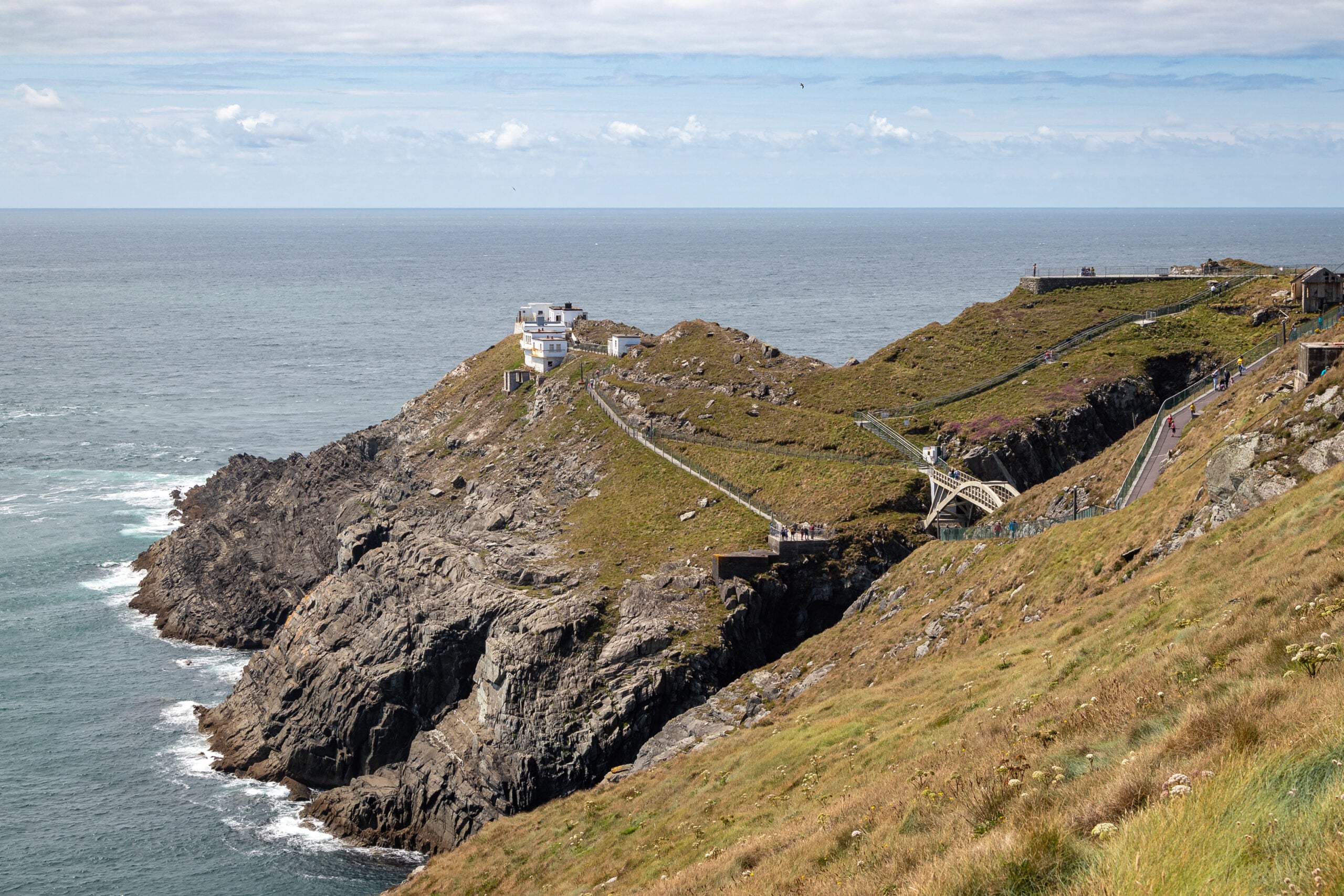 Aerial view of Mizen Head signal station in County Cork, with its white lighthouse buildings on the headland and the footbridge crossing to the mainland