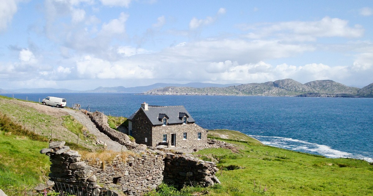 Stone cottage on a rugged cliffside above the Atlantic, evoking West Cork's wild coastal scenery