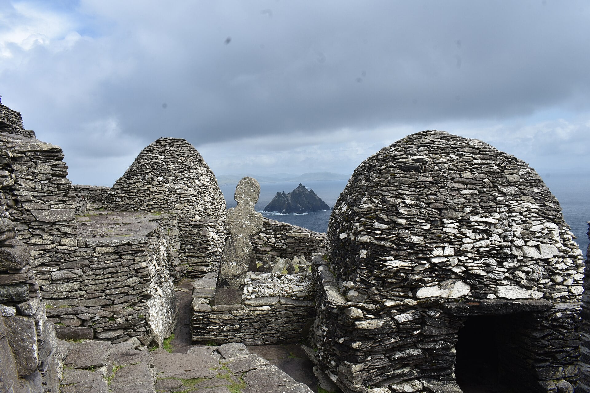 Stone beehive huts (cloch&aacute;in) atop Skellig Michael, with Small Skellig visible in the distance