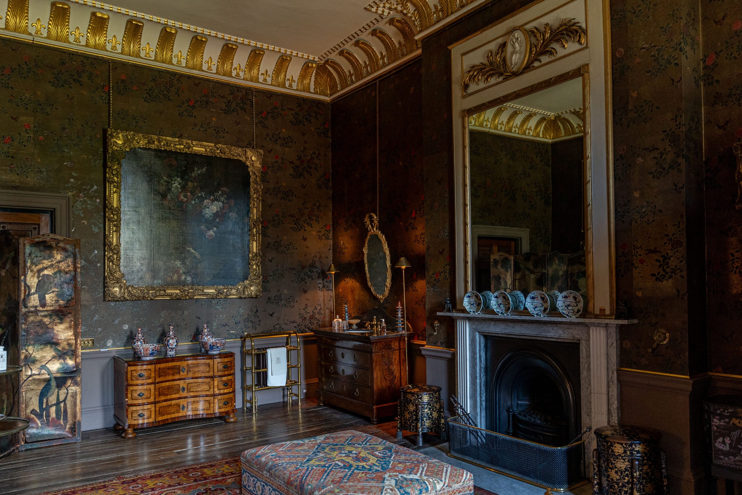 An ornate Georgian-era interior room with gilded ceiling cornicing and antique furniture