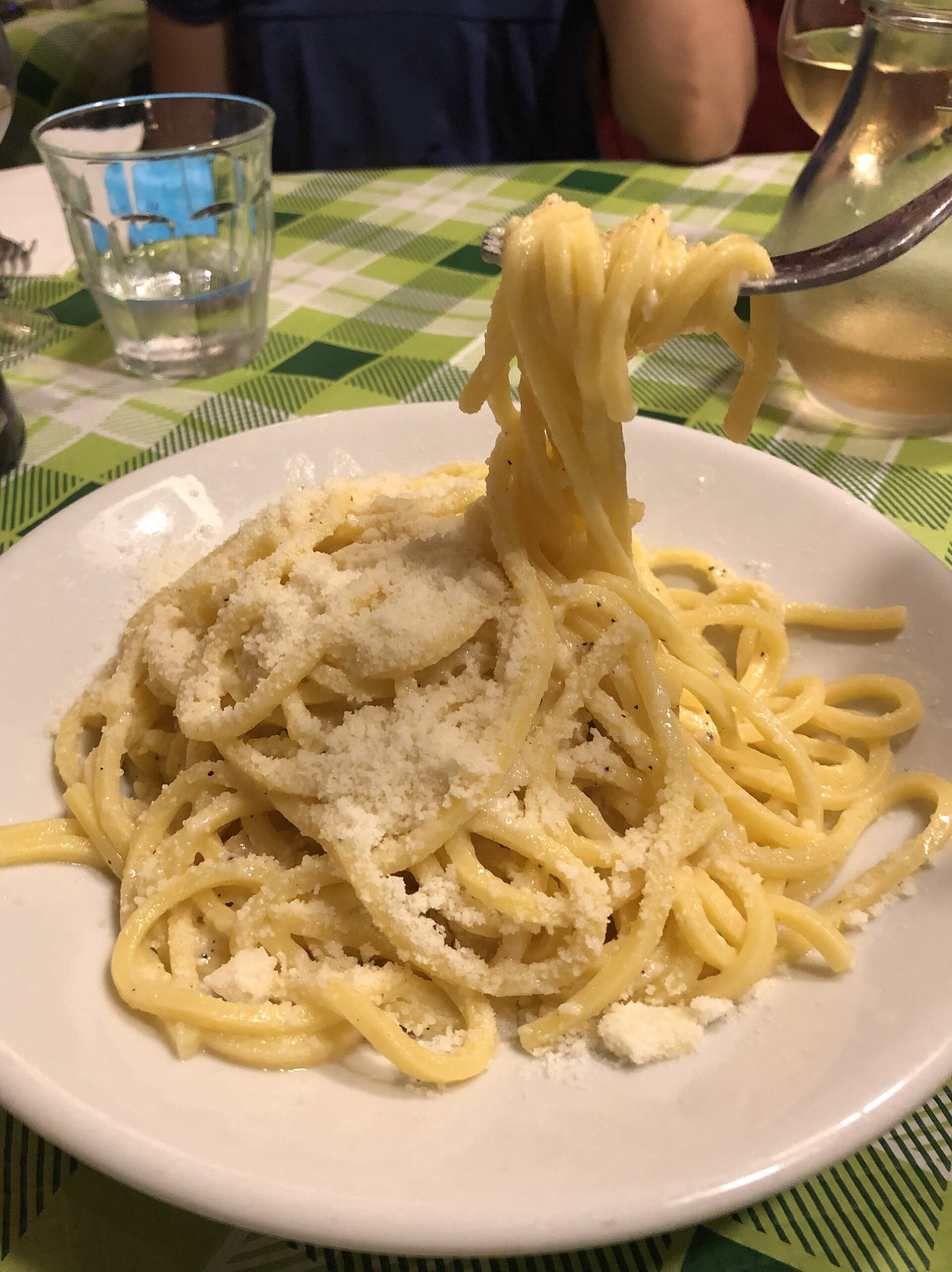 Forkful of cacio e pepe spaghetti coated in glossy pecorino and black pepper sauce, at a trattoria in Rome