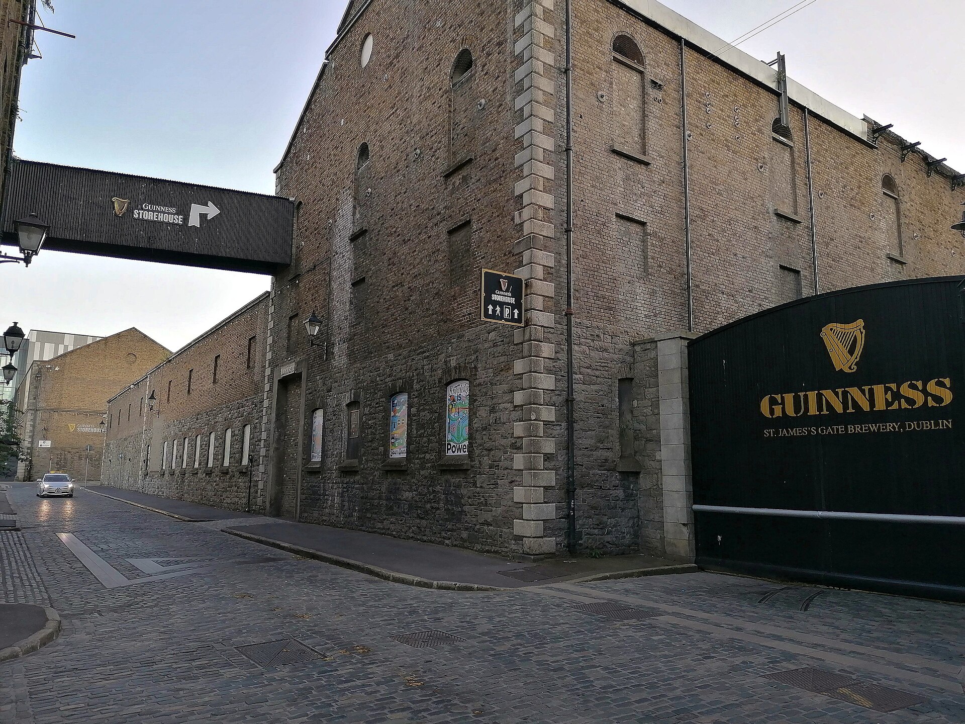 Brick brewery buildings and the black Guinness gate at St. James's Gate Brewery, Dublin, with a Guinness Storehouse sign overhead