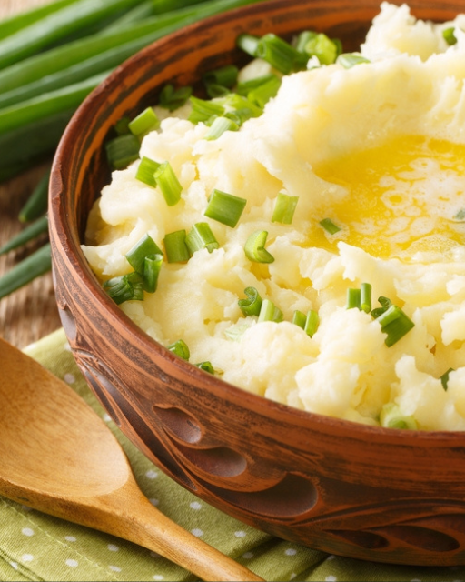A wooden bowl of traditional Irish champ, mashed potato with spring onion and a well of melted butter