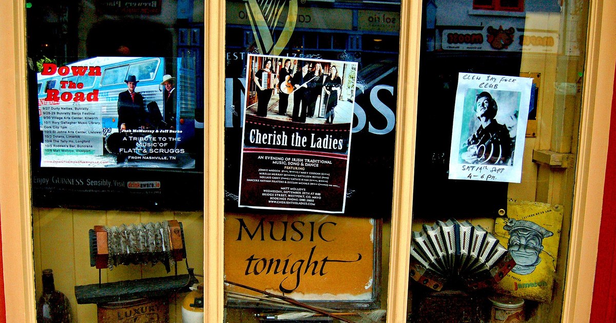 Window display at Matt Molloy's pub in Westport with live-music gig posters, a concertina, and a 'Music tonight' sign