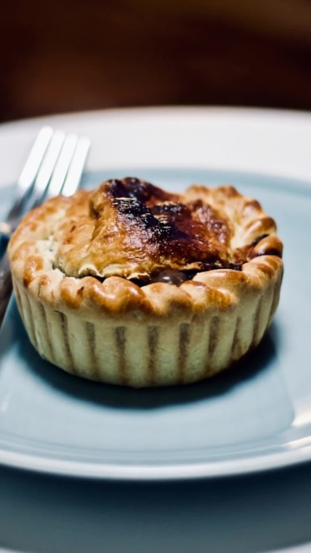 Golden-crusted individual beef and Guinness pie on a blue plate, poster image for the Irish Food, As It Really Is video