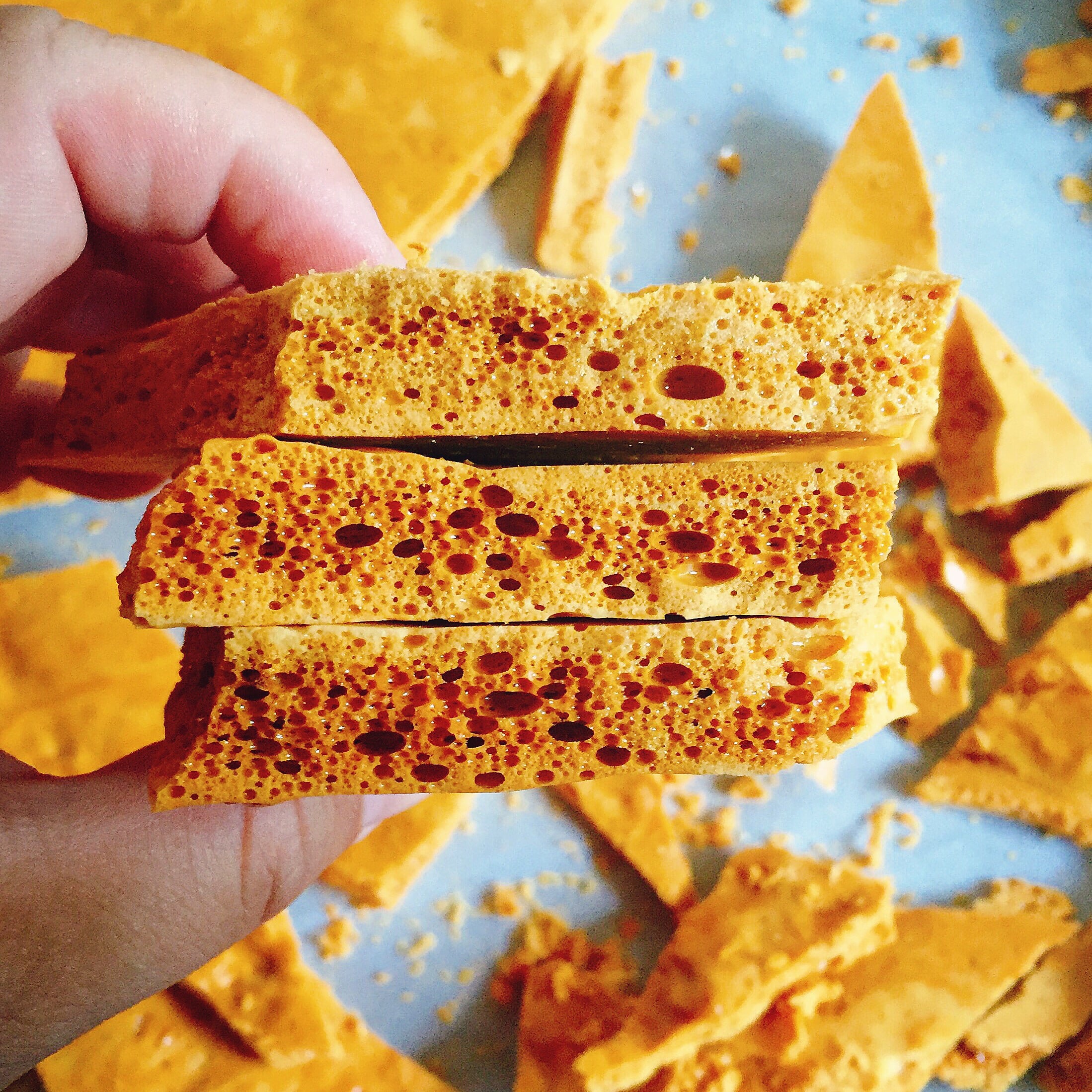Broken shards of golden honeycomb toffee, similar to traditional yellowman, showing the airy, bubbled texture created when bicarbonate of soda is added to boiling syrup