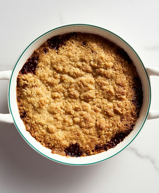 A freshly baked apple crumble with a golden topping in a white dish