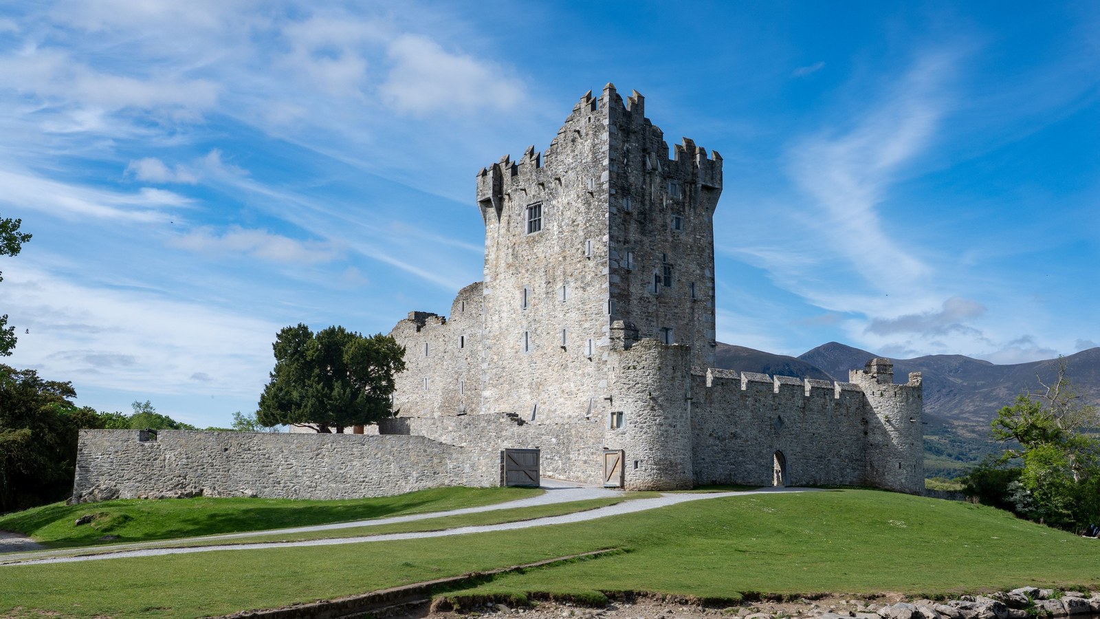 Ross Castle, a stone tower house with its bawn wall, on the shore of Lough Leane in Killarney, County Kerry