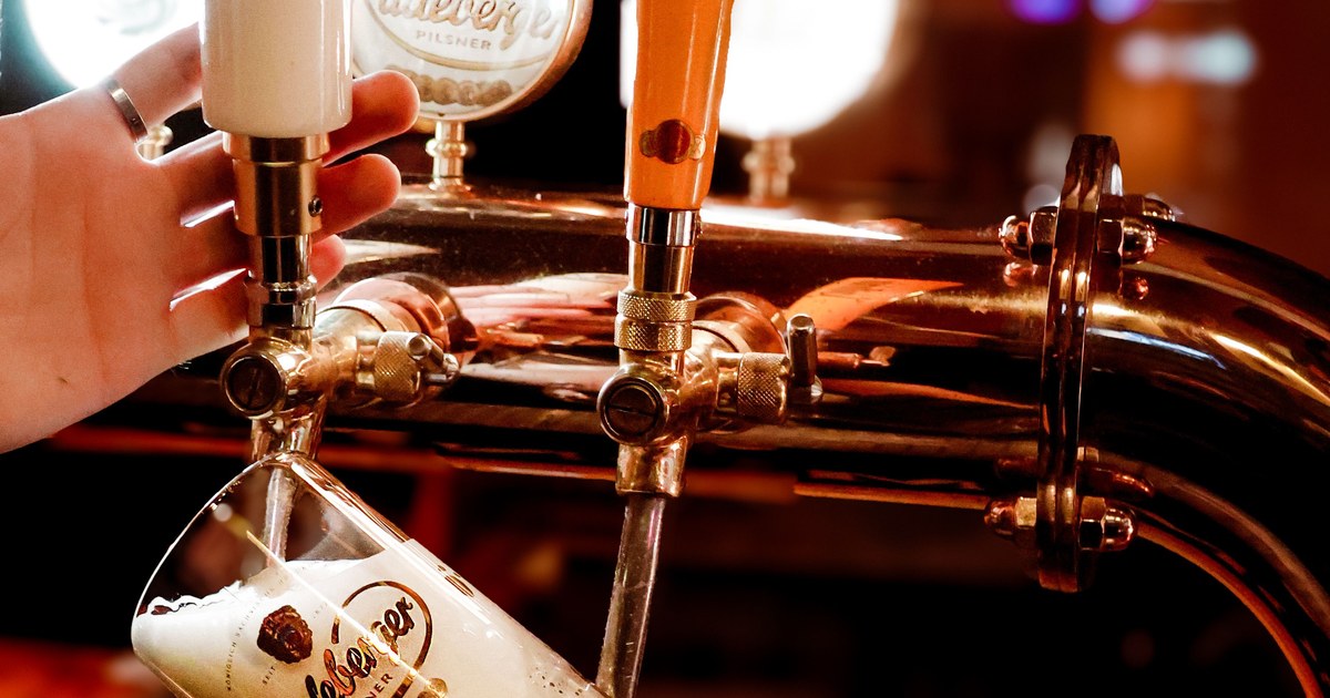 Bartender pouring a pint from the beer taps at a craft beer bar