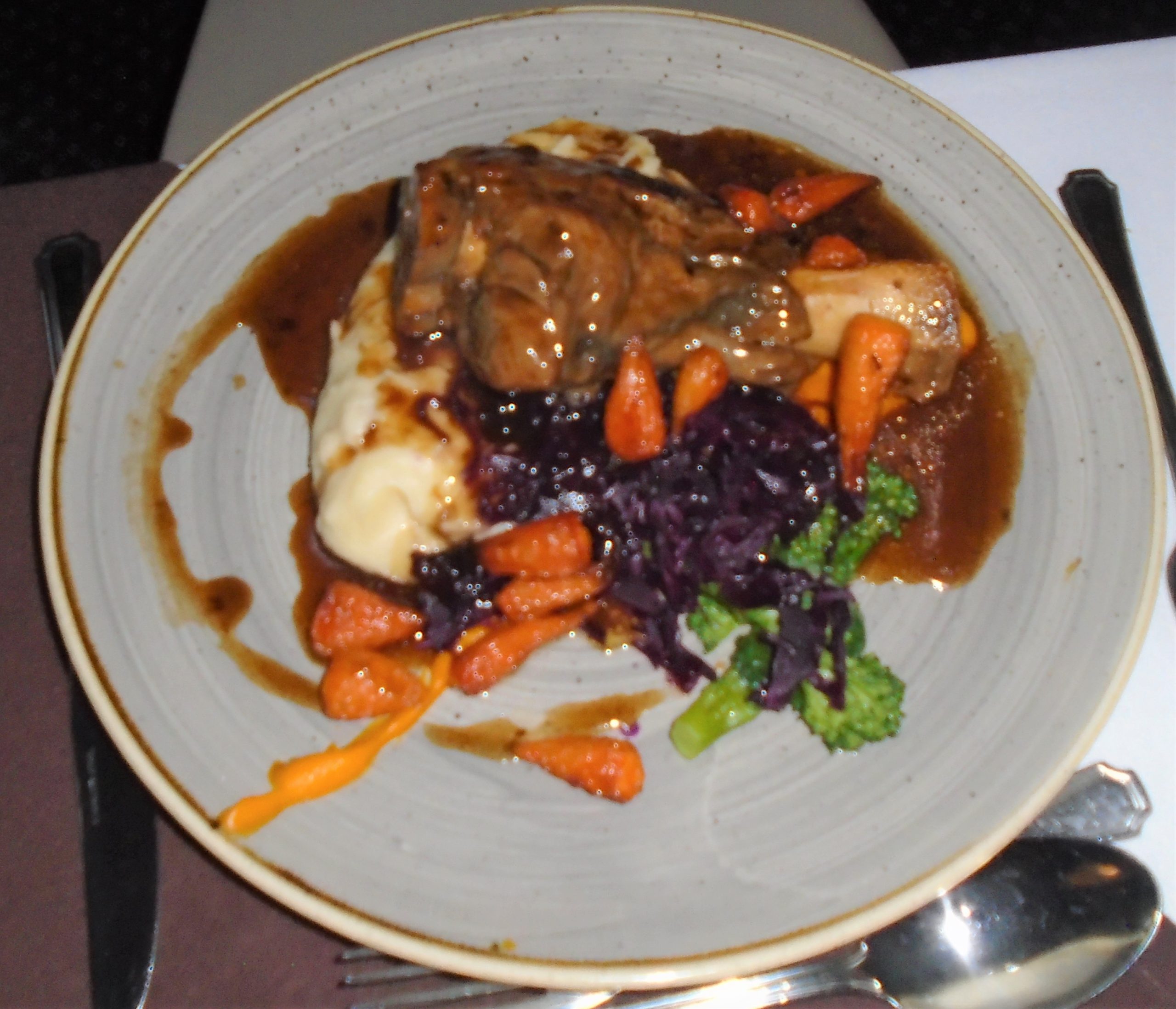 Braised lamb shank in rich gravy with buttered mash, honey-roasted carrots and braised red cabbage