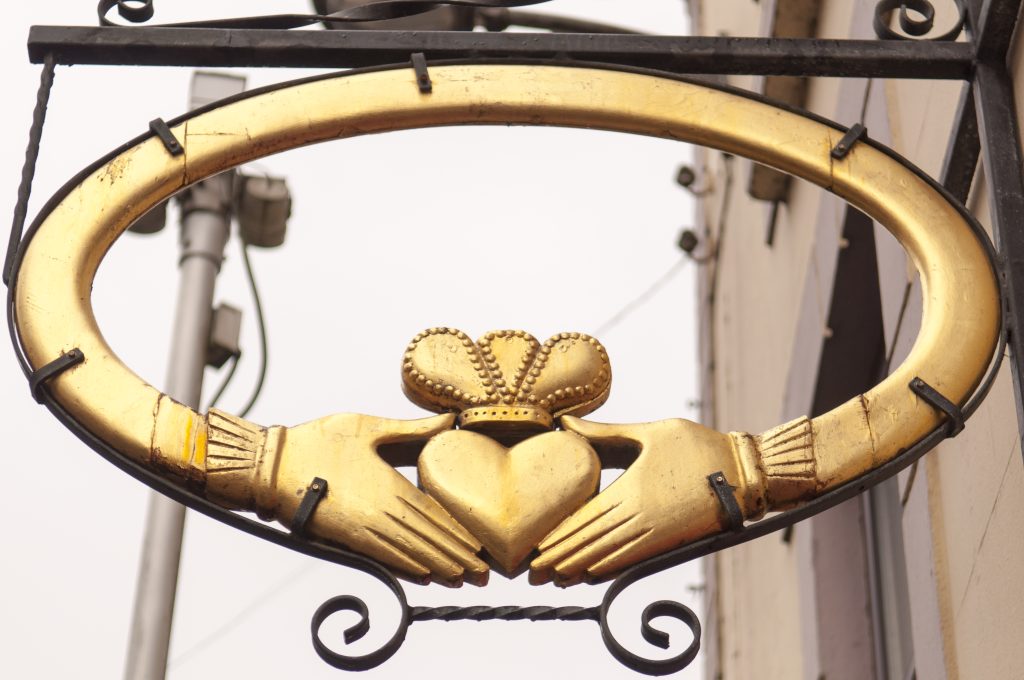 Golden Claddagh ring sign in Galway, showing the two hands holding a crowned heart