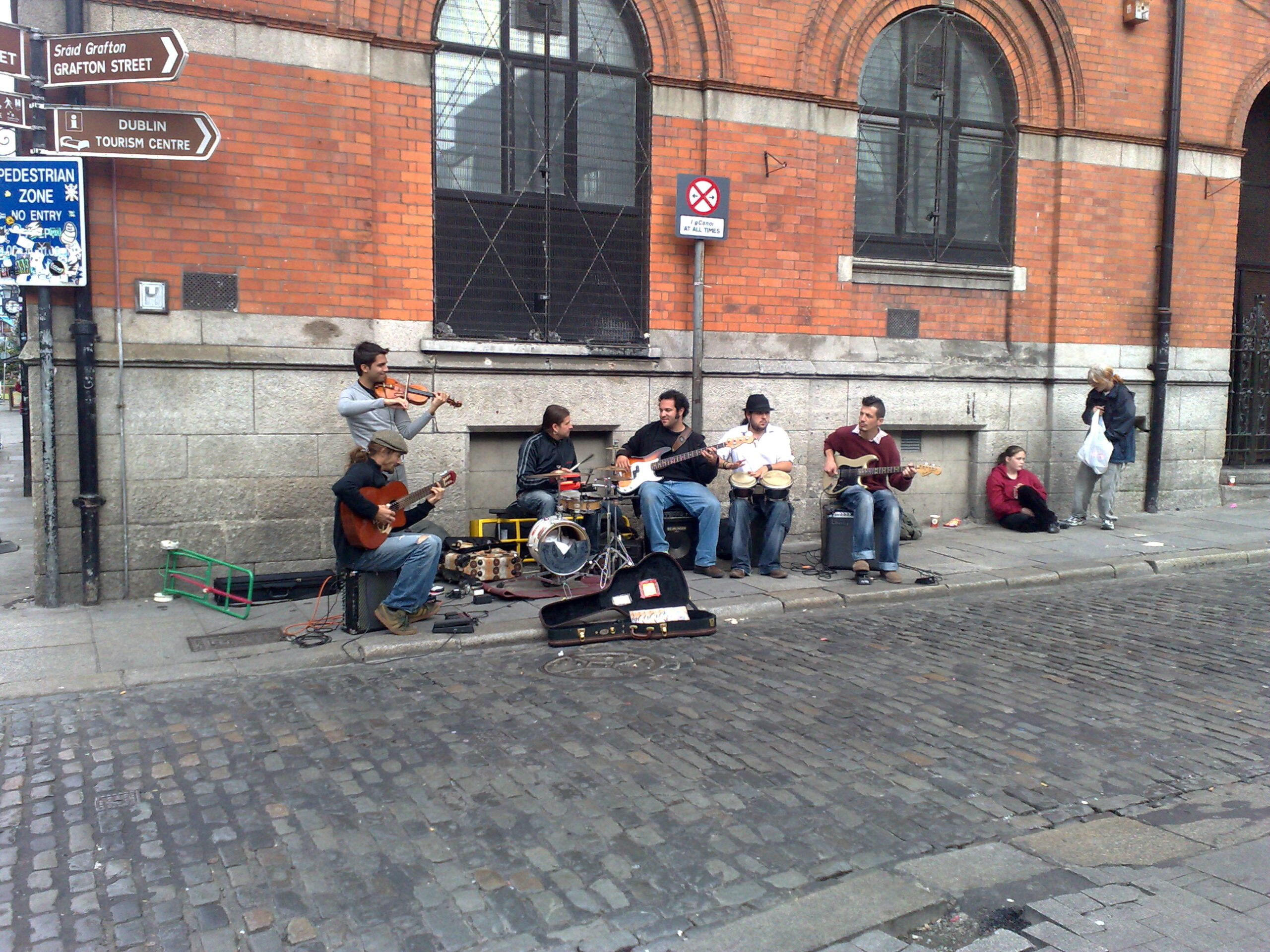 Street musicians busking with fiddle, guitars and bongos on a cobbled street near Temple Bar and Grafton Street in Dublin