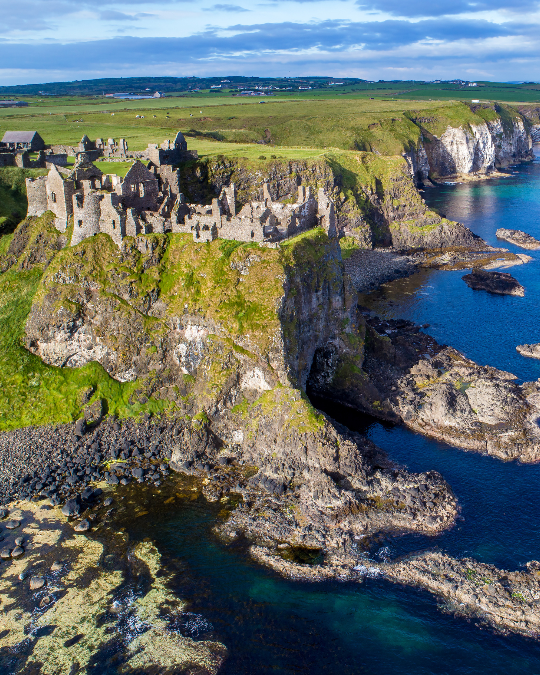Aerial view of the ruins of Dunluce Castle perched on a cliff above the Atlantic coast, County Antrim, Northern Ireland