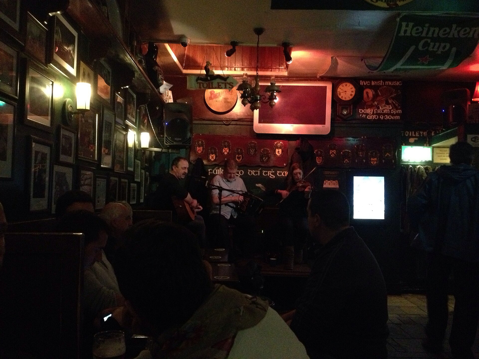 Musicians playing guitar, accordion, and fiddle at a traditional Irish music session in Taaffes Bar, Galway