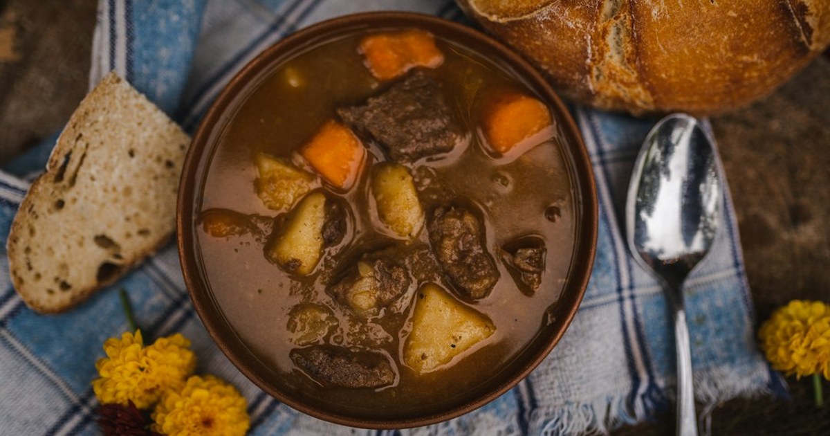 Bowl of slow-braised Irish venison casserole with carrots and potatoes, served with crusty bread
