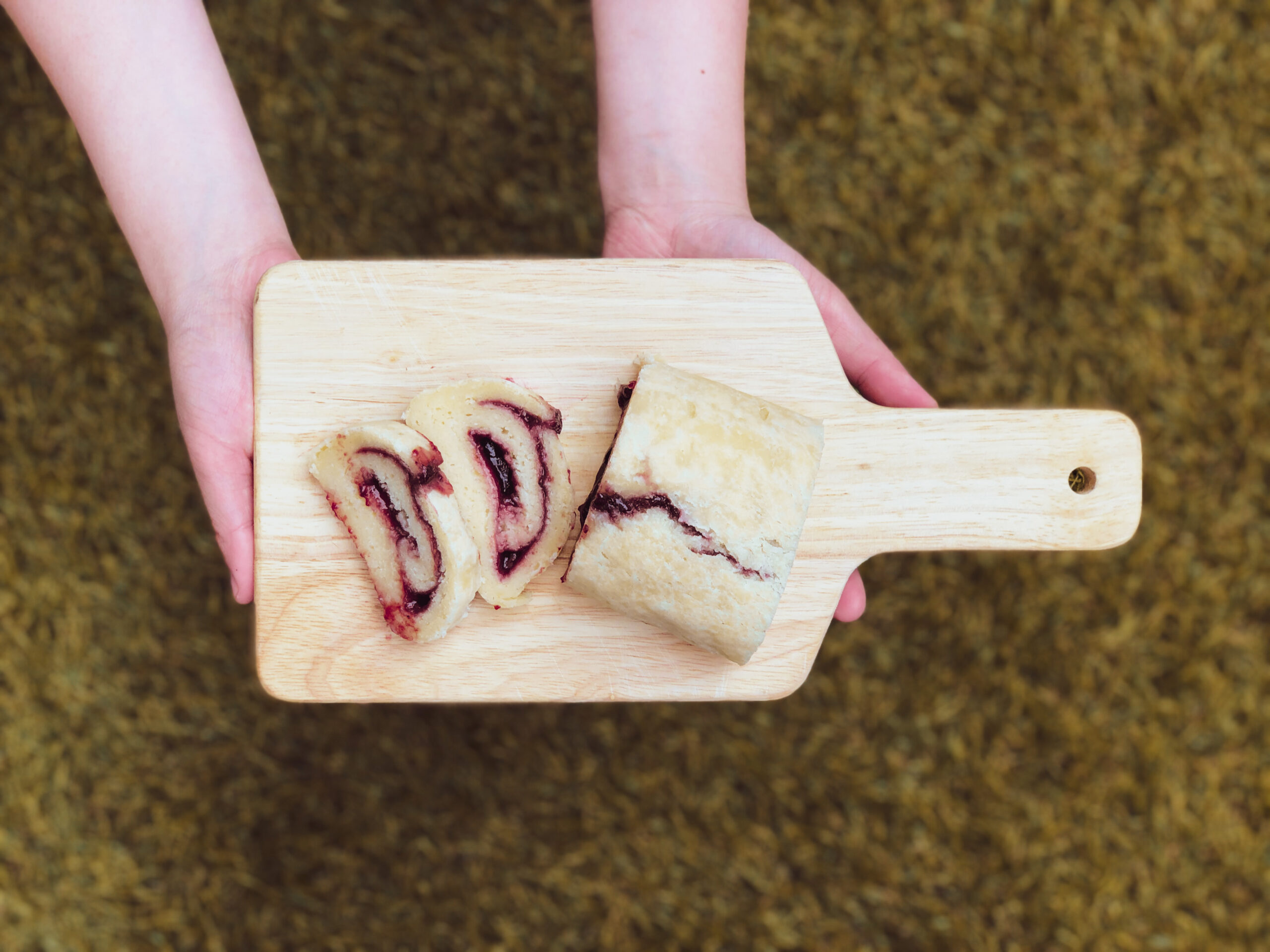 Sliced jam roly-poly pudding rounds on a wooden board, showing the classic jam swirl