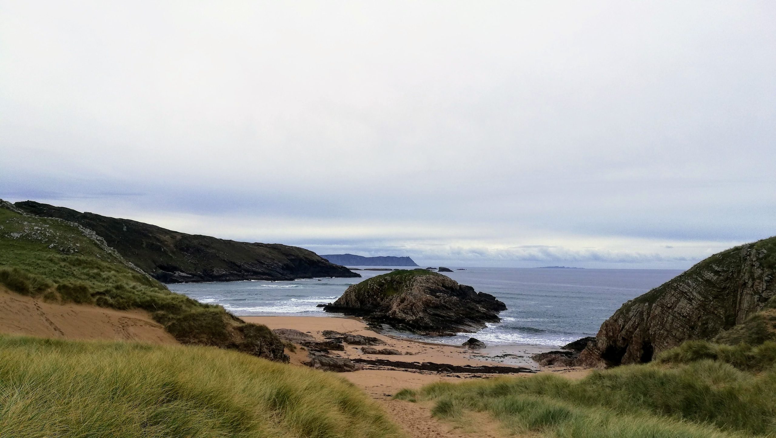 Boyeeghter Strand (Murder Hole Beach), a sheltered cove of white sand enclosed by dark headland on the Rosguill Peninsula, County Donegal