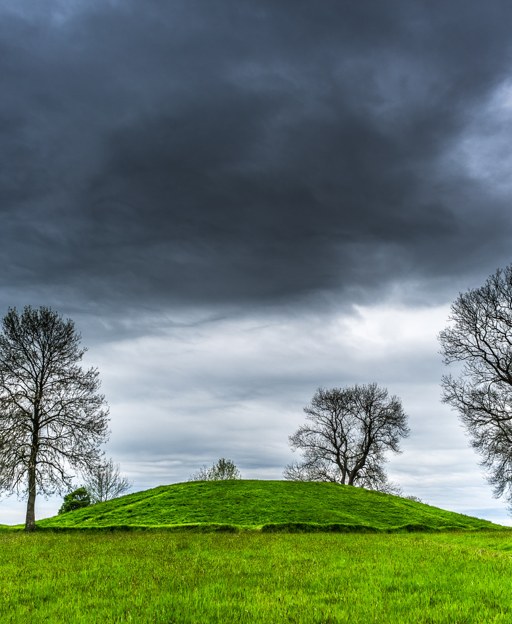 The grassy mound of Navan Fort, Emain Macha, under a dark sky in County Armagh