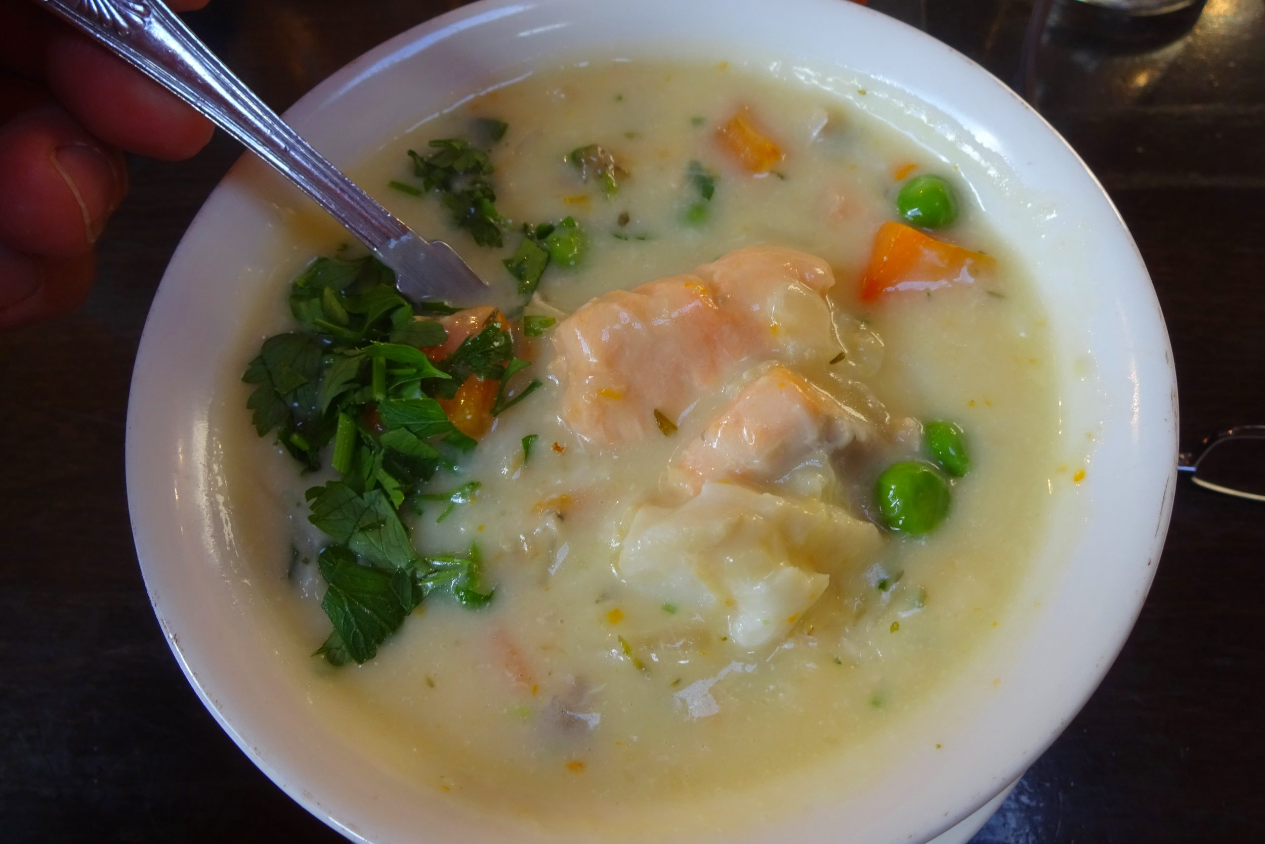 Bowl of creamy Irish-style seafood chowder with chunks of white fish, carrot, peas and chopped parsley