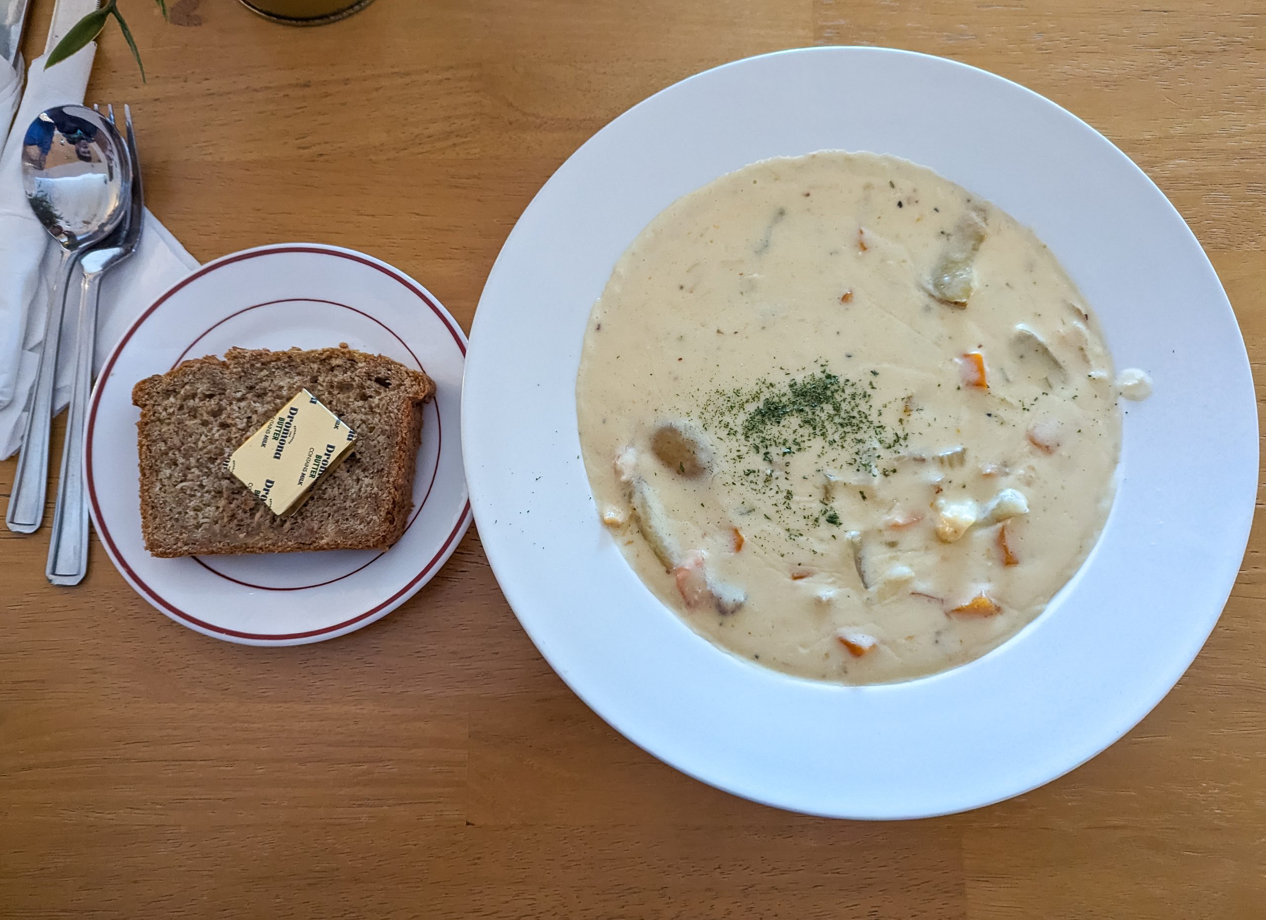 Creamy smoked haddock chowder in a white bowl served with Irish brown soda bread and butter