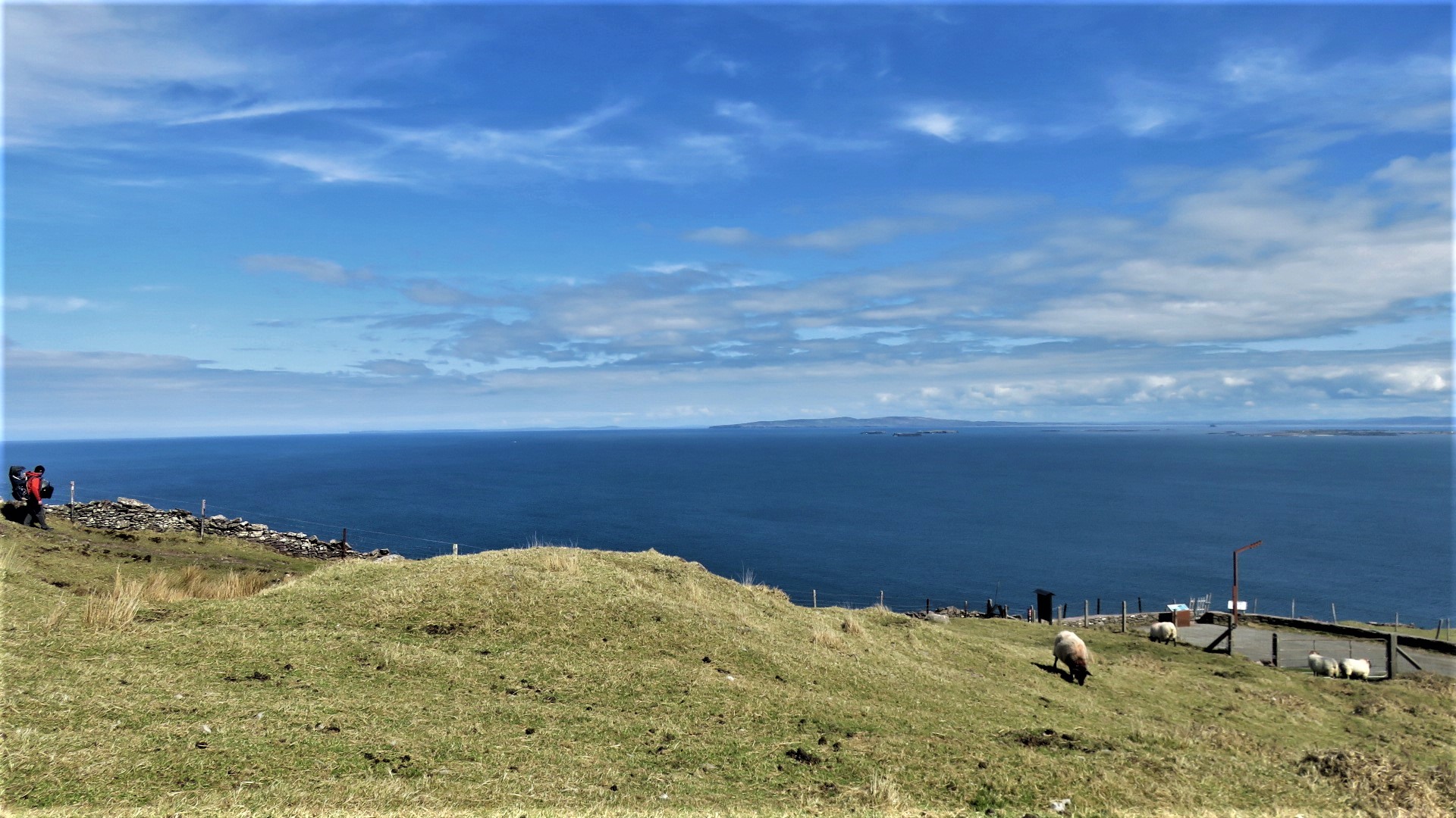 Solo hiker with backpack pausing on the cliffside trail above the Atlantic on the Dingle Peninsula, County Kerry, Ireland