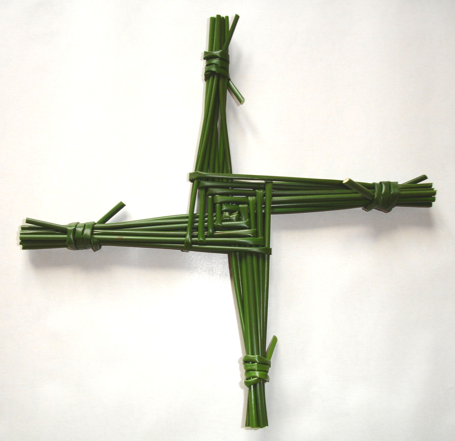 A traditional St Brigid's Cross woven from green rushes, with a central square and four radiating arms, the Irish symbol hung over doors each February