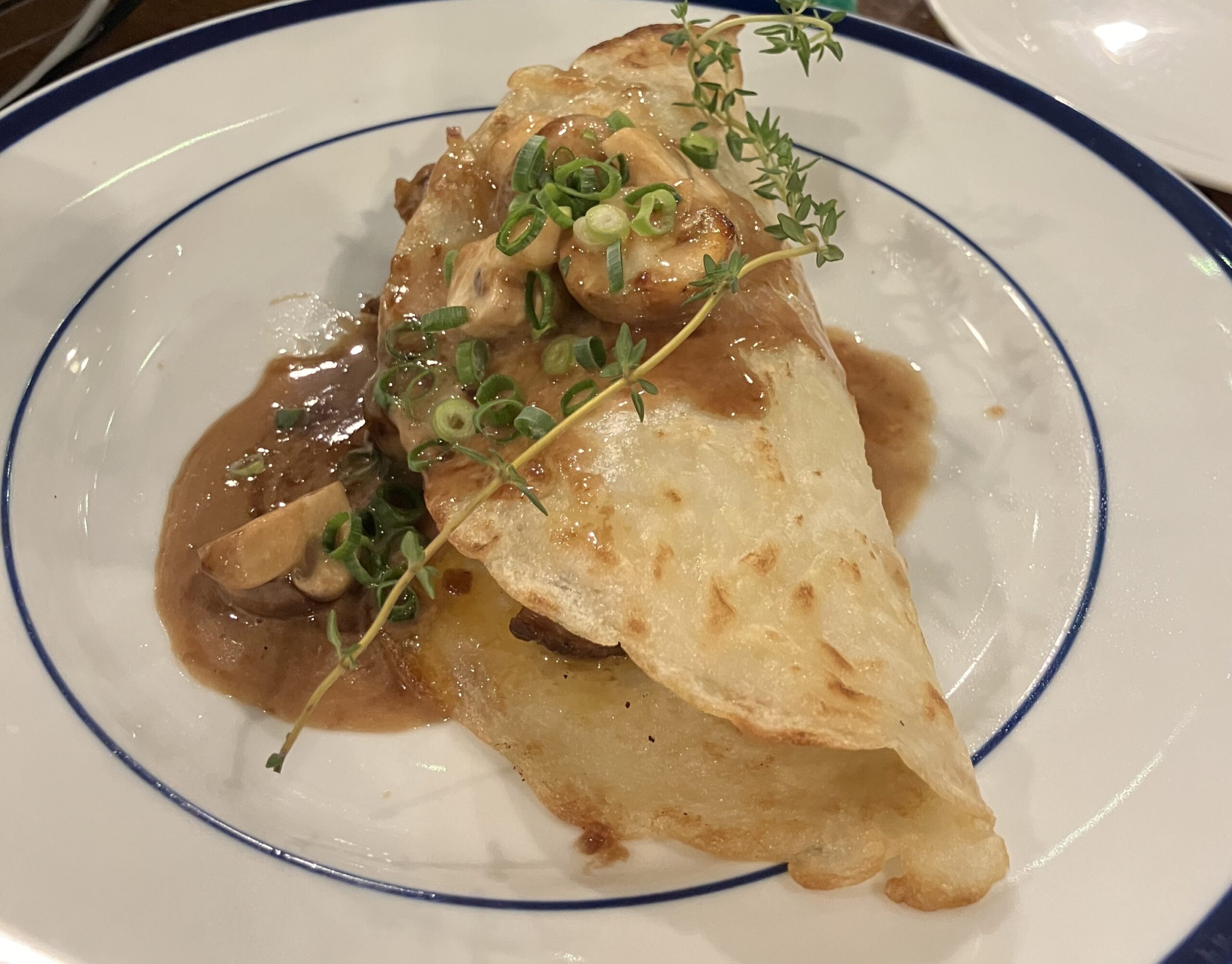 Thin boxty pancake rolled around a mushroom and spring onion filling, served with gravy