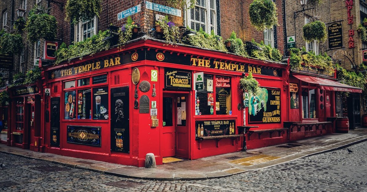 The red-painted exterior of The Temple Bar pub in Dublin's Temple Bar district, with hanging flower baskets and traditional pub signage